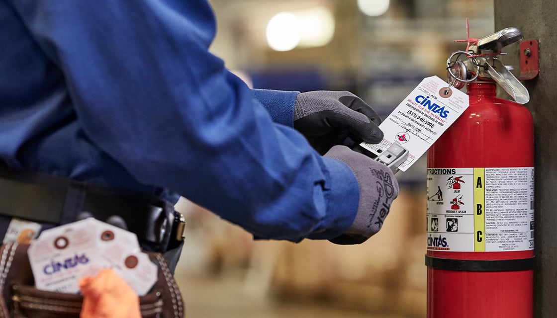 cintas representative holding a fire extinguisher tag
