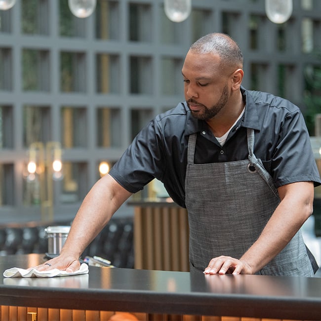 bartender wiping down bar in food service apron